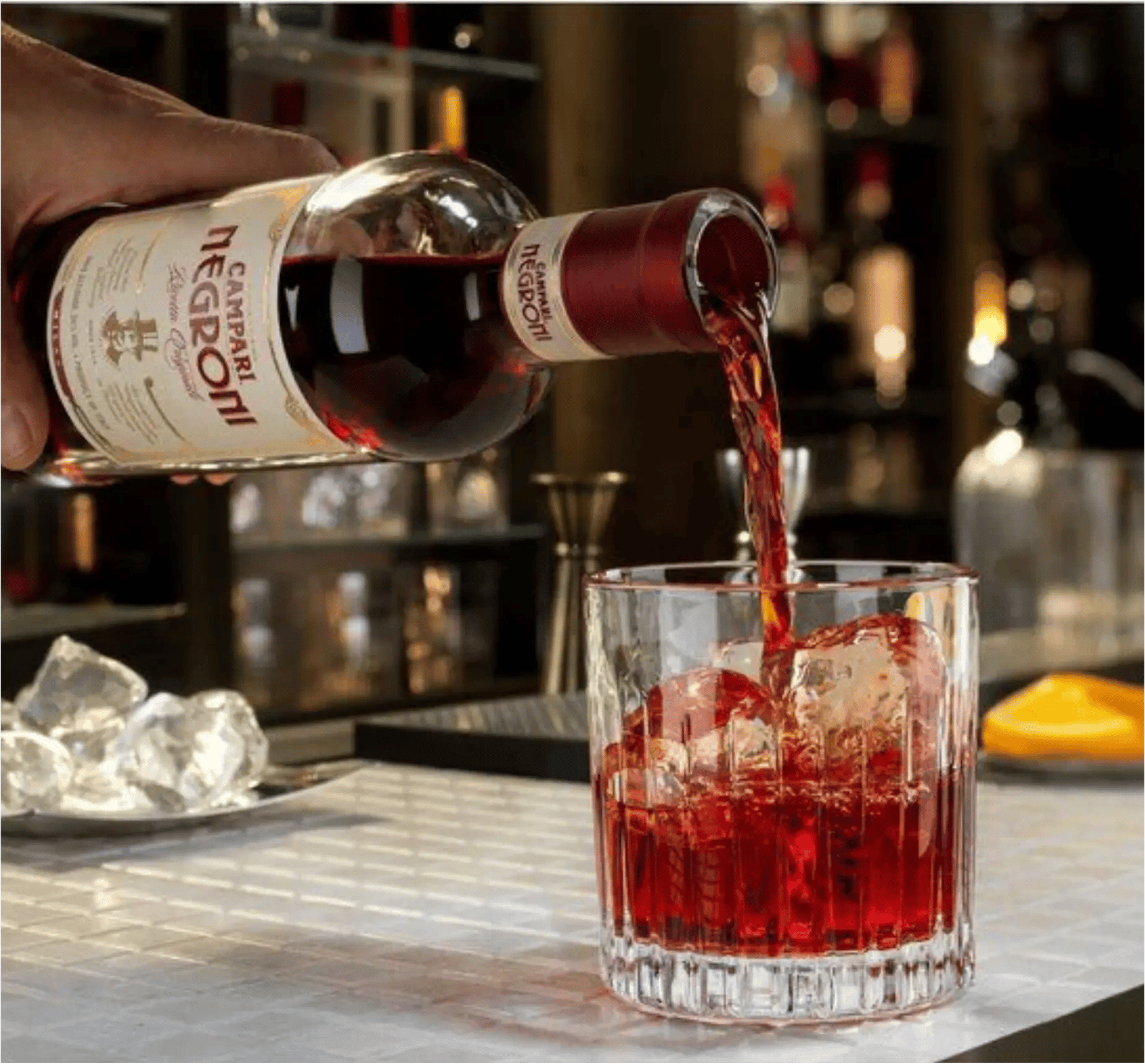 campari negroni poured into glass at a bar